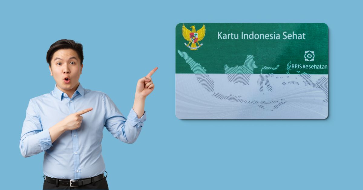  A man in a blue shirt points at a green and white Indonesian health insurance card with text reading: "Kartu Indonesia Sehat" and "BPJS Kesehatan" with a surprised expression on his face.